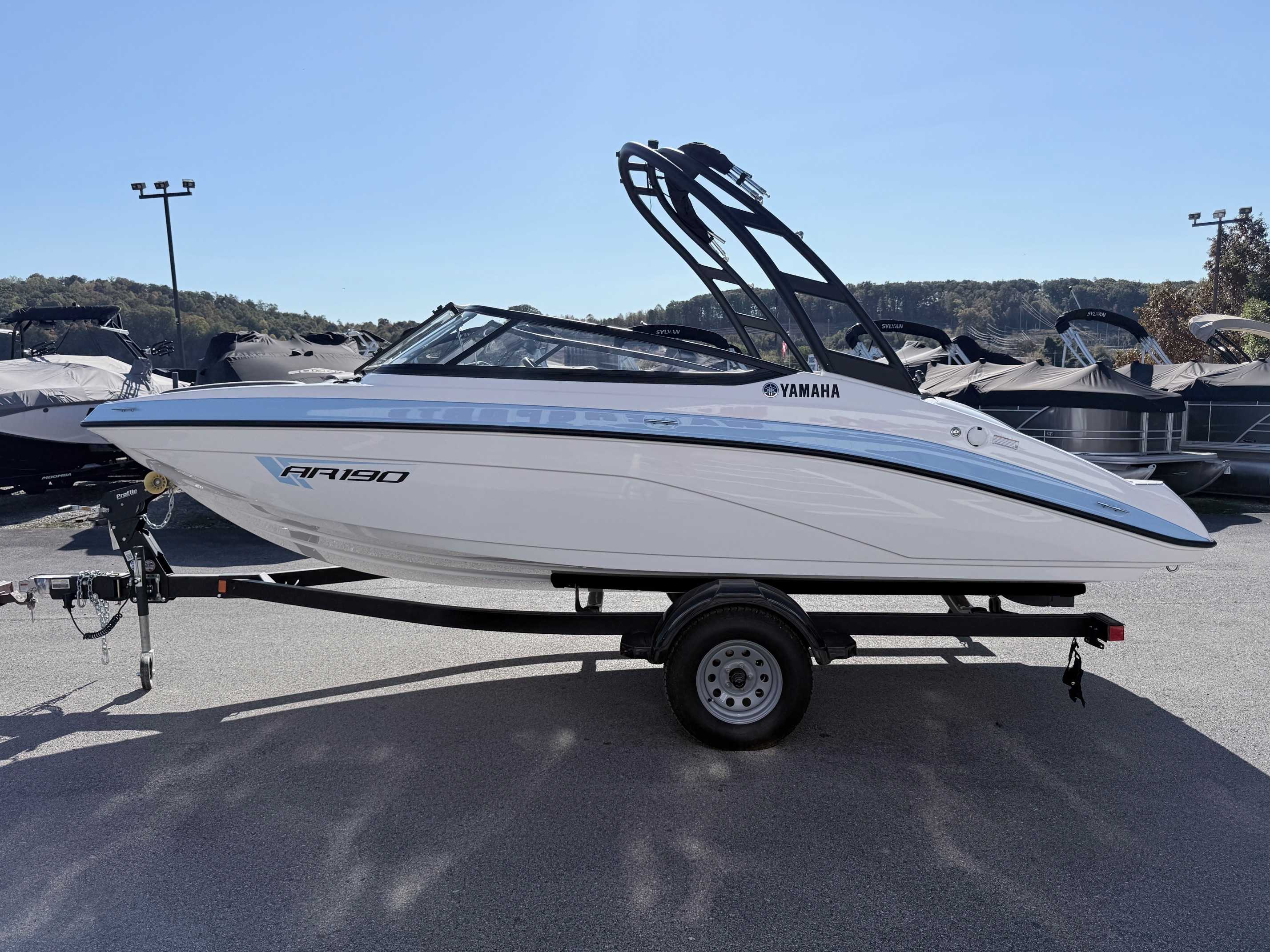 White Yamaha AR190 bowrider boat with black wakeboard tower on trailer at dealership